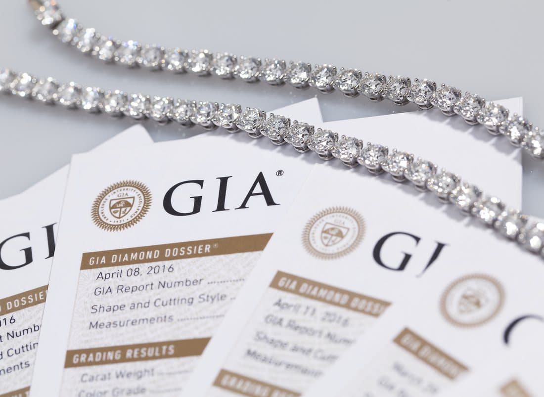 Diamond tennis necklaces laid over GIA Diamond Dossier reports