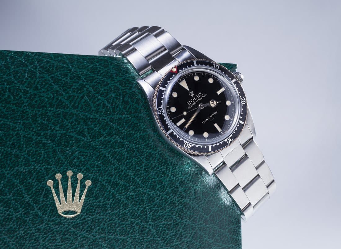 A silver Rolex Turn-O-Graph resting on a dark green Rolex presentation box