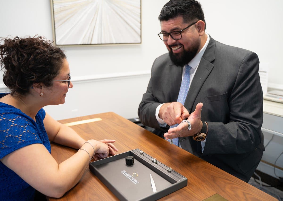 A Diamond Banc expert presenting a diamond bracelet to a seated client across an office desk